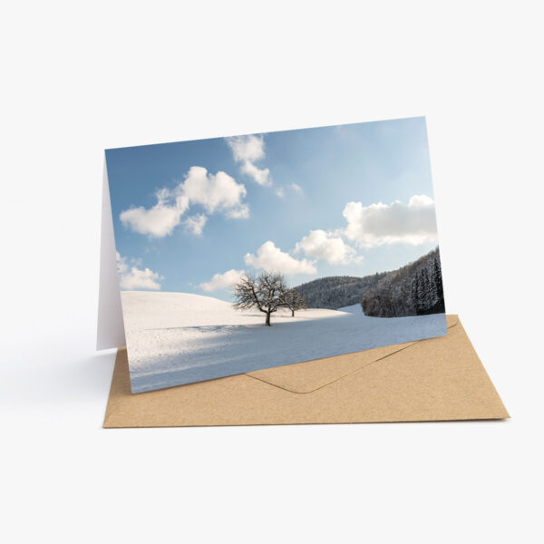 Grusskarte mit Winter Fotografie: Schneebedeckte Landschaft mit blauem Himmel und weissen Wolken.